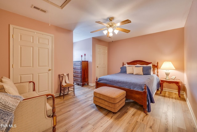 bedroom featuring baseboards, light wood-type flooring, attic access, and ceiling fan
