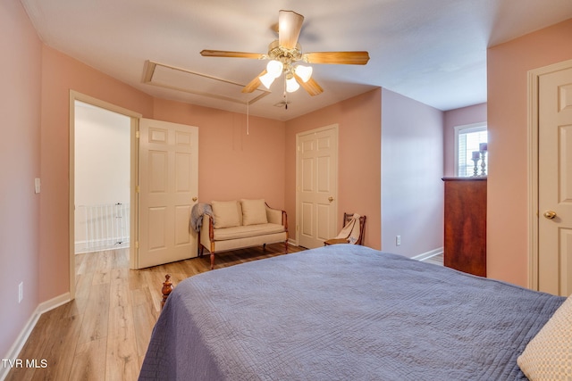 bedroom with attic access, wood finished floors, baseboards, and a ceiling fan