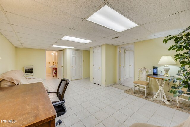 office area with a drop ceiling, light tile patterned flooring, and heating unit