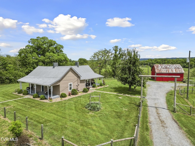 view of front of home featuring a front lawn, a porch, fence, and an outbuilding