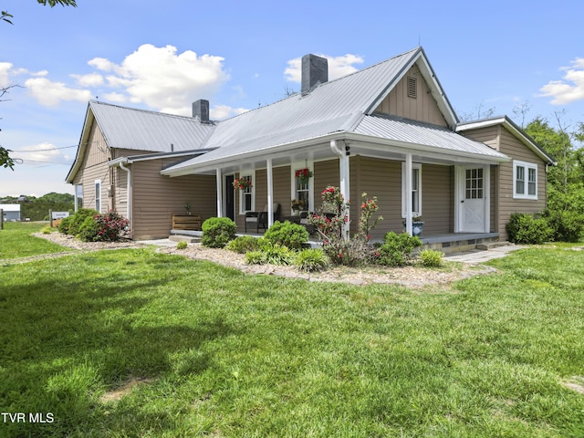 country-style home with a front lawn, a chimney, and metal roof