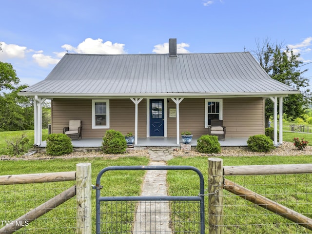 country-style home featuring a front lawn, metal roof, and covered porch