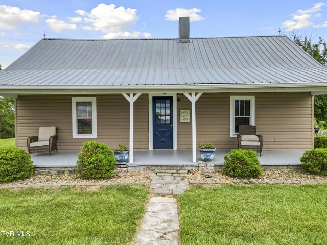rear view of property featuring covered porch and metal roof