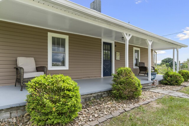 doorway to property featuring a chimney and covered porch