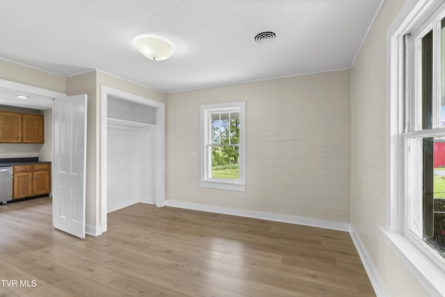 interior space featuring crown molding, baseboards, visible vents, and light wood-style floors