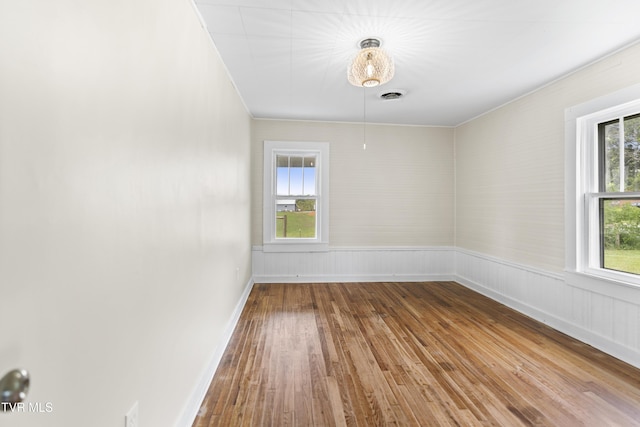 empty room featuring visible vents, baseboards, and hardwood / wood-style floors