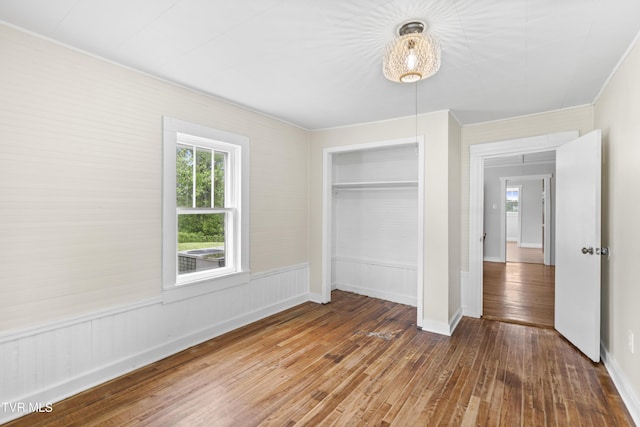 unfurnished bedroom with wood-type flooring, a closet, and baseboards