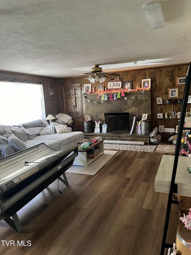 6430 Hoot Owl Hollow Rd, Norton, VA 24273 - living room featuring a textured ceiling, wood finished floors, a stone fireplace, and wood walls