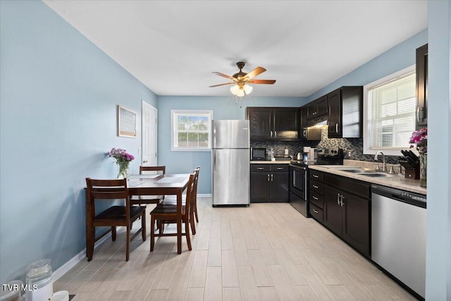 kitchen featuring a sink, stainless steel appliances, ceiling fan, decorative backsplash, and light countertops
