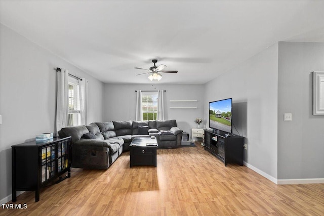 living room featuring a ceiling fan, baseboards, and light wood finished floors