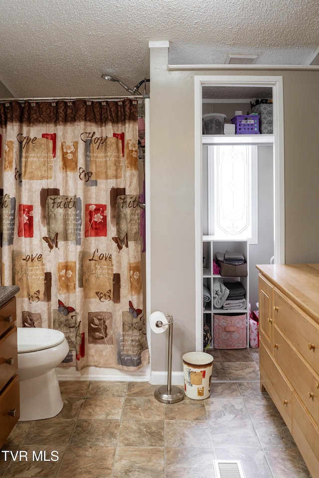 full bath featuring a textured ceiling, visible vents, toilet, and vanity