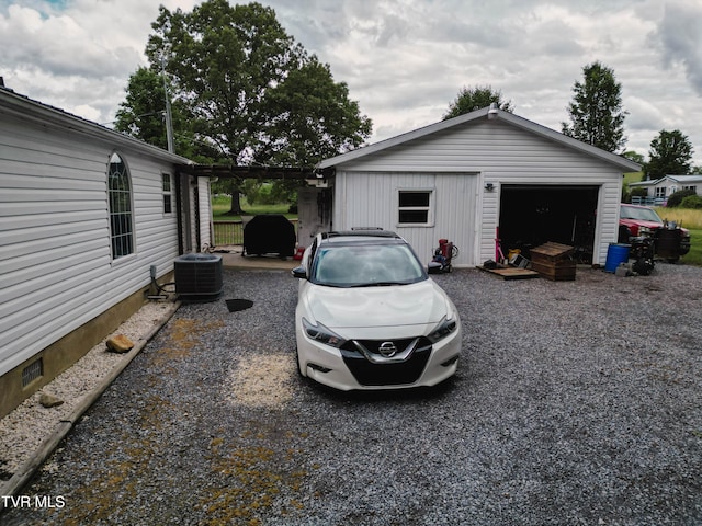 exterior space featuring central AC unit, driveway, a garage, and an outbuilding