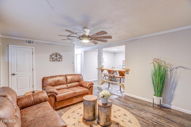 living area with a ceiling fan, baseboards, ornamental molding, visible vents, and wood finished floors