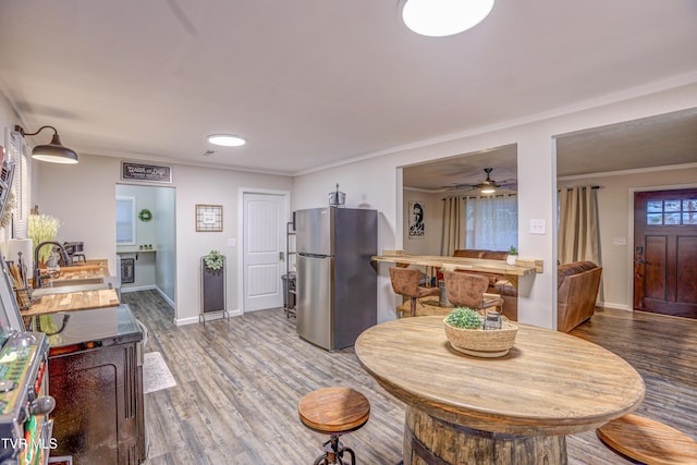 interior space with ceiling fan, ornamental molding, baseboards, and wood finished floors