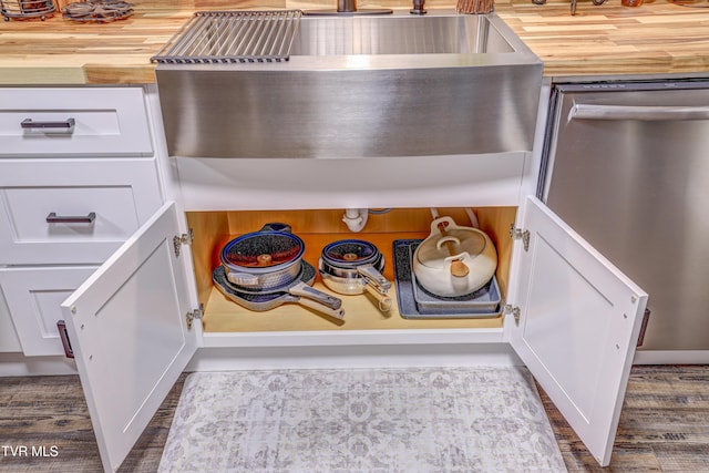 interior details with dishwasher, wooden counters, a sink, white cabinets, and dark wood-style floors