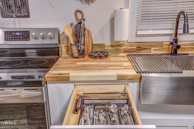 interior details featuring butcher block countertops, a sink, and electric stove