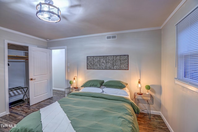 bedroom with baseboards, crown molding, visible vents, and wood finished floors