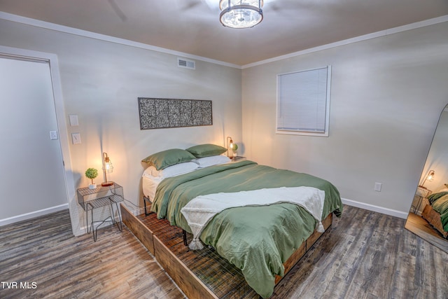 bedroom featuring wood finished floors, ornamental molding, visible vents, a chandelier, and baseboards