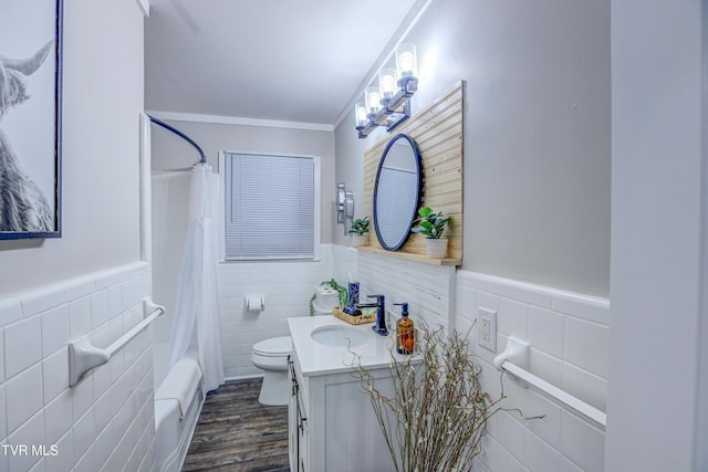 bathroom featuring tile walls, toilet, vanity, a wainscoted wall, and wood finished floors