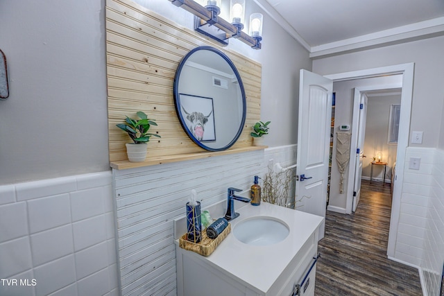 bathroom with tile walls, visible vents, vanity, a wainscoted wall, and wood finished floors