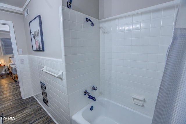 bathroom featuring wood finished floors, a wainscoted wall, shower / tub combo, tile walls, and visible vents