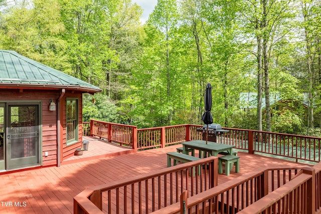 deck with a forest view and outdoor dining space