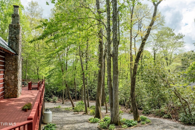 view of yard with a deck and a view of trees