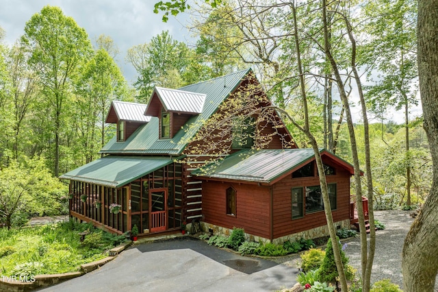view of property exterior with metal roof and a sunroom