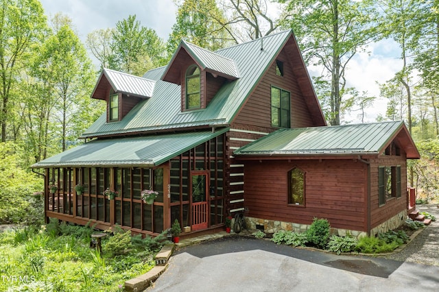 back of property with metal roof and a sunroom