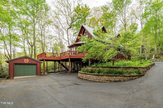 view of front of property with an outbuilding, a wooden deck, aphalt driveway, and stairs