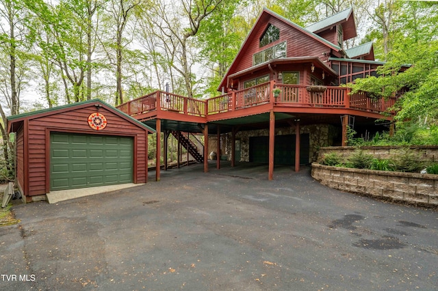 log cabin featuring stone siding, a deck, aphalt driveway, stairway, and an outbuilding