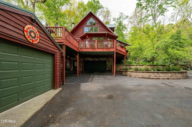 view of front of property featuring metal roof, a wooden deck, stone siding, and driveway