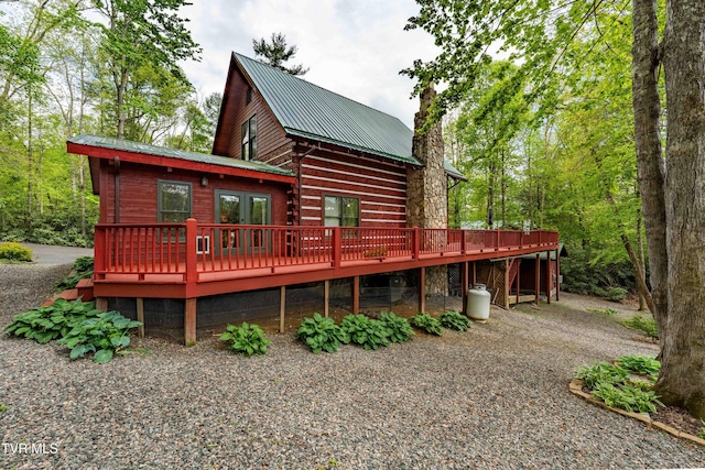 back of house featuring a chimney, metal roof, and a wooden deck