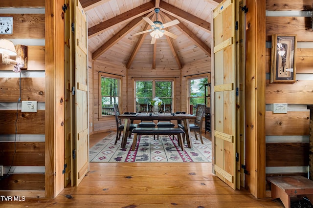 dining room featuring wood walls, light wood-style flooring, ceiling fan, and wood ceiling