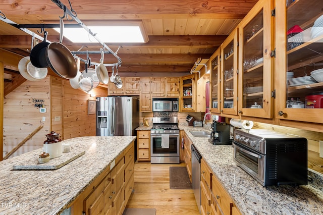 kitchen featuring a toaster, a sink, light wood-style floors, stainless steel appliances, and beam ceiling