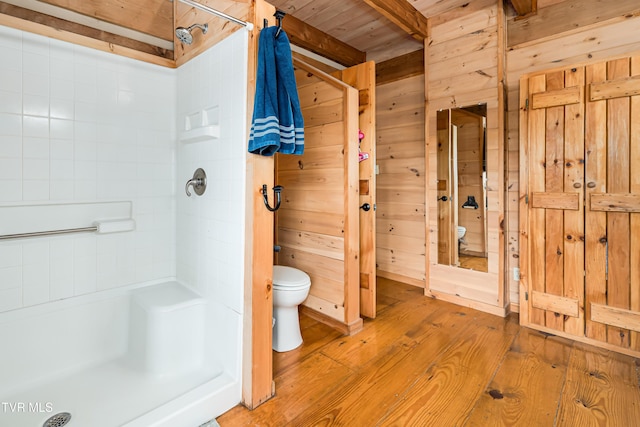 full bathroom with toilet, wooden walls, wood finished floors, and a shower stall