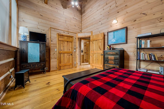 bedroom featuring wood walls, wood-type flooring, and a towering ceiling