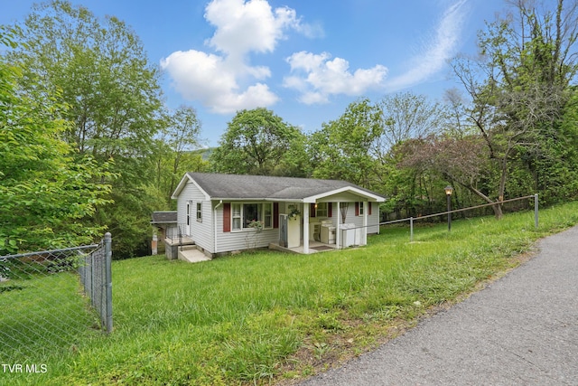 view of front facade with covered porch, roof with shingles, fence, and a front yard