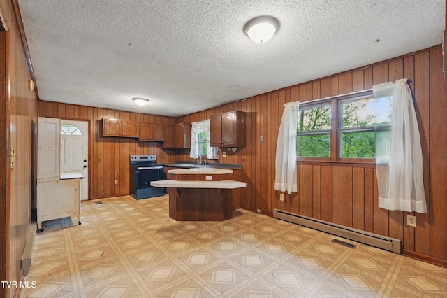 kitchen featuring a peninsula, a wealth of natural light, stainless steel electric range oven, and baseboard heating