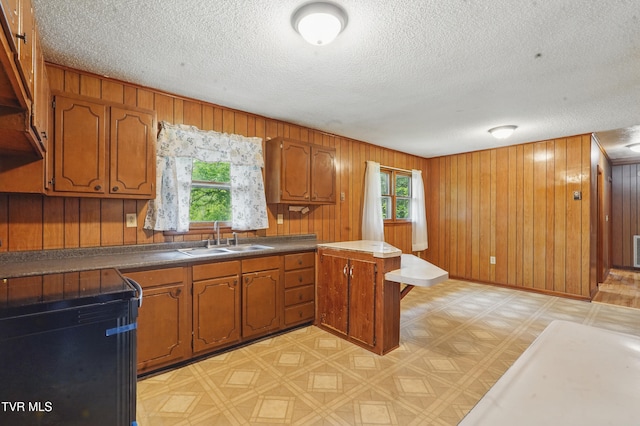 kitchen with brown cabinets, light floors, a peninsula, and a sink