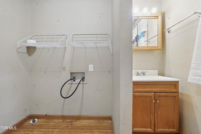 laundry area featuring a sink, wood finished floors, laundry area, baseboards, and hookup for a washing machine