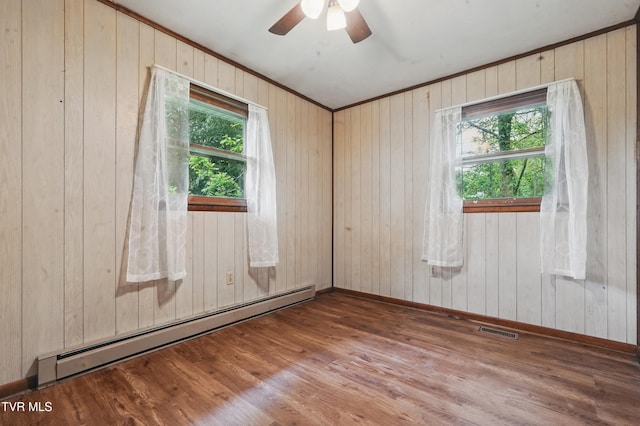 spare room featuring a wealth of natural light, visible vents, wood finished floors, and a baseboard radiator