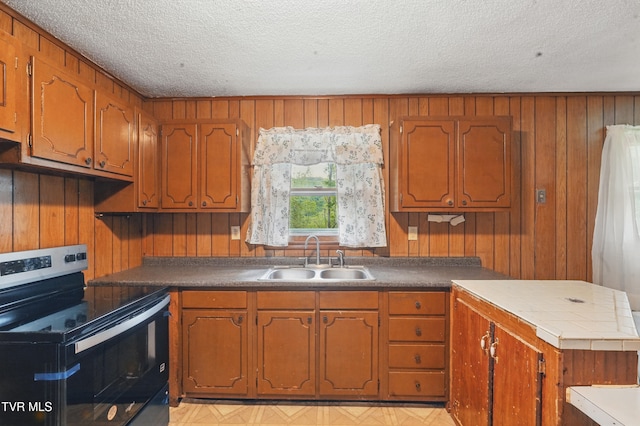 kitchen featuring brown cabinets, a sink, and stainless steel electric stove