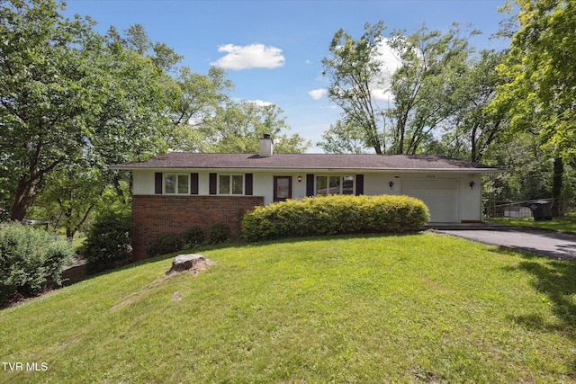 ranch-style house with an attached garage, driveway, brick siding, a front yard, and a chimney