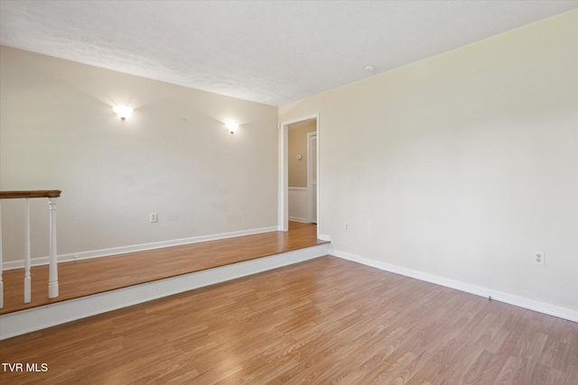 unfurnished room with wood finished floors, baseboards, and a textured ceiling