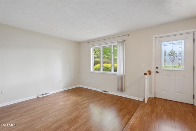 entrance foyer with light wood finished floors, baseboards, and a textured ceiling