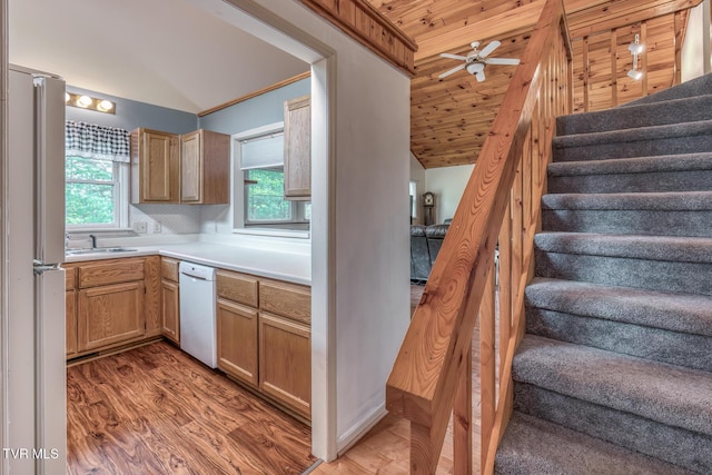 kitchen featuring a sink, white appliances, light wood-type flooring, vaulted ceiling, and light countertops