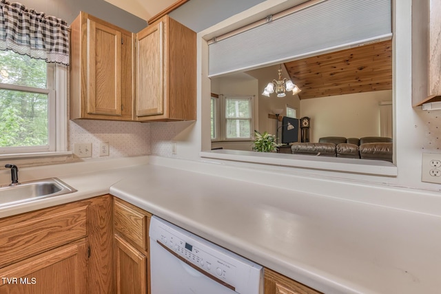kitchen featuring white dishwasher, a notable chandelier, a sink, open floor plan, and light countertops