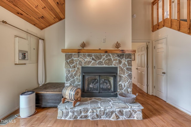interior details with electric panel, baseboards, a stone fireplace, and wood finished floors