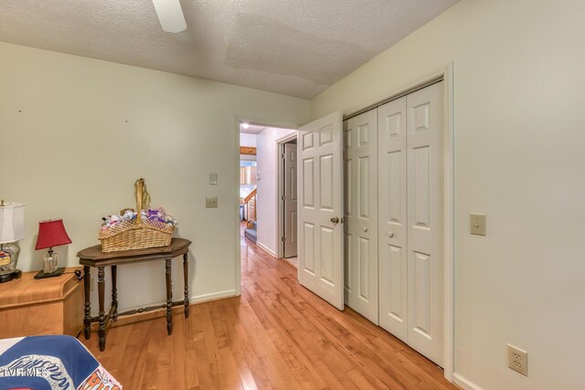 interior space with light wood-type flooring, baseboards, and a textured ceiling
